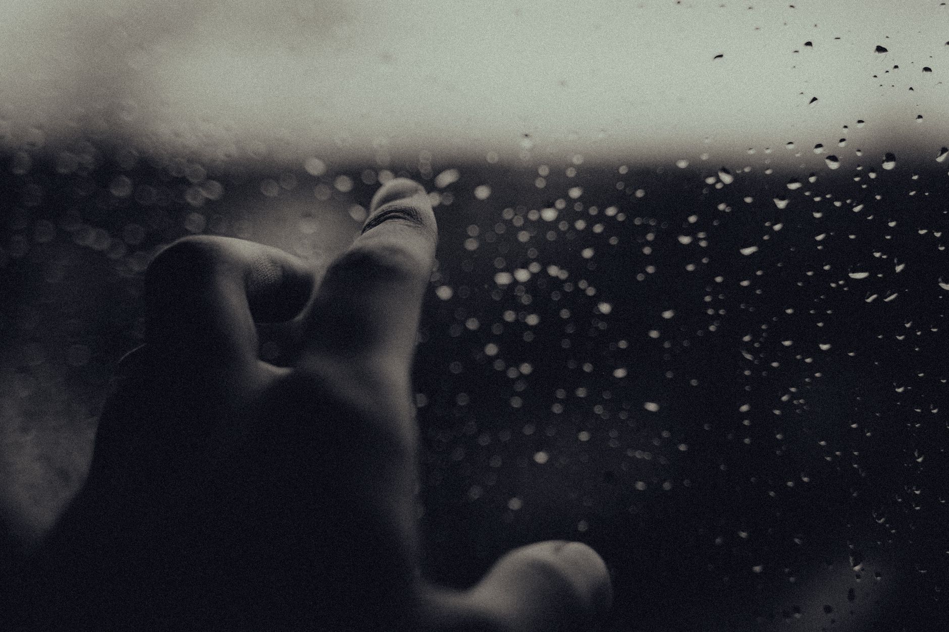 pointing on a glass with rain drops